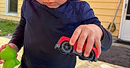Daniel is registered to the contest to win money with this photo: child, toddler, curly_hair, sunglasses, toy_car, rubber_duck, swim_trunks, kiddie_pool, water, summer, outdoor, play, yellow_house, sunny_day, striped_clothing, blue_shirt, hands, concrete, door, window