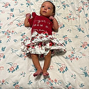Kenlee Grayce joined the competition — help win amazing prizes! baby, infant, child, lying_down, floral_pattern, bedspread, red_clothing, skirt, cute, indoors, person, looking_up, barefoot, fabric, soft_lighting, comfortable, young, sleepwear, skin, head