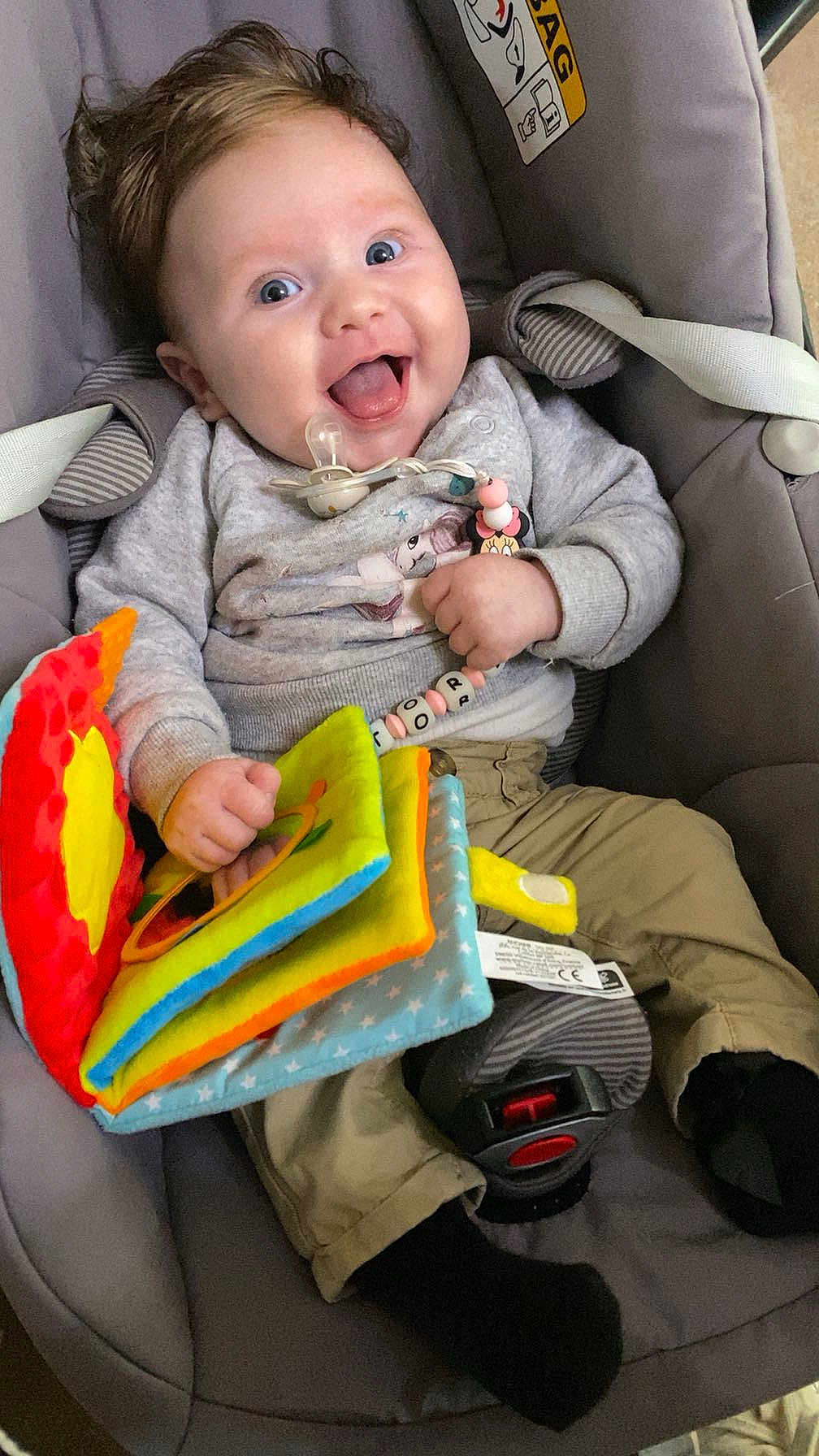 Victoria a rejoint le concours — aidez-le/la à gagner de superbes lots ! baby, car_seat, child, clothing, colorful, cute, happy, indoor, infant, pacifier, pants, person, playful, portrait, seatbelt, smiling, sock, soft_toy, sweater, toy