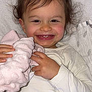 Naïssa participe au concours pour gagner de l'argent avec cette photo : toddler, child, smiling, happy, blanket, pink, hair, face, teeth, white_clothing, hands, indoor, portrait, cute, baby, soft_texture, comfort, closeup, skin, expression