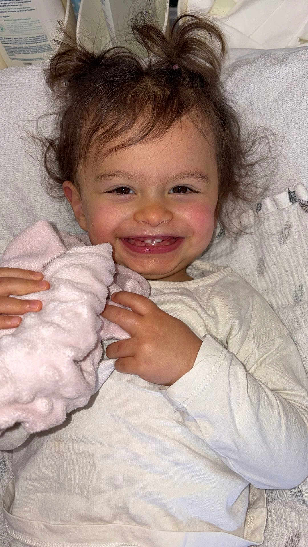 Naïssa participe au concours pour gagner de l'argent avec cette photo : toddler, child, smiling, happy, blanket, pink, hair, face, teeth, white_clothing, hands, indoor, portrait, cute, baby, soft_texture, comfort, closeup, skin, expression