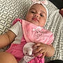 baby, infant, pacifier, headband, pink_bib, clothing, hand, bedspread, pattern, person, face, closeup, indoor, cute, child, resting, holding, baby_girl, soft_lighting, casual