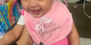 Aurélia joined the competition — help win amazing prizes! baby, child, pink_bib, headband, smiling, indoor, person, happy, clothing, footwear, hand, blanket, baby_clothes, toy, carpet, room, face, cute, infant, holding