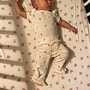 Arianna joined the competition — help win amazing prizes! baby, infant, child, sleeping, lying_down, portrait, face, hands, arms, legs, onesie, strawberry_pattern, floral_bedding, mattress, crib, bedroom, indoor, warm_lighting, candid, baby_fashion