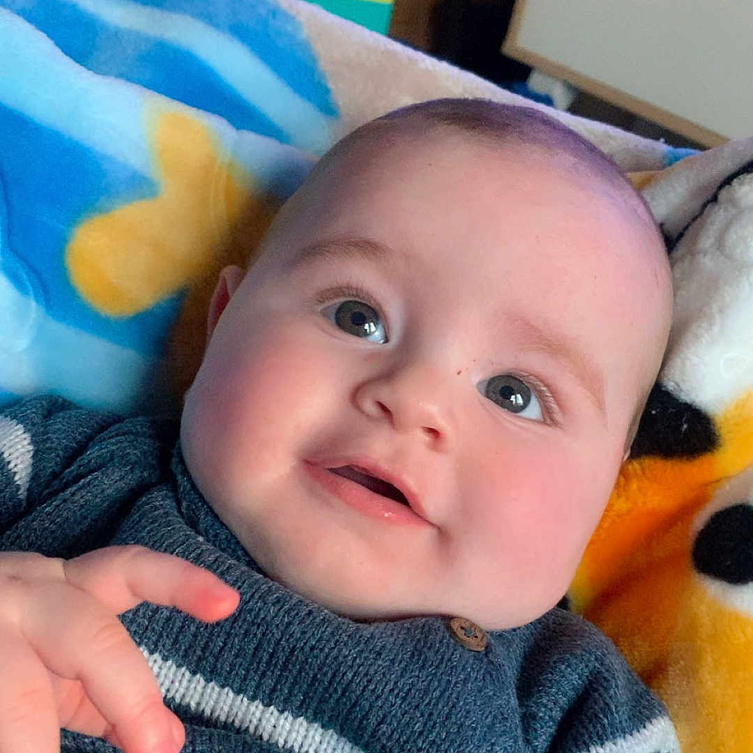 Dylan a rejoint le concours — aidez-le/la à gagner de superbes lots ! baby, blanket, box, child, clothing, cozy, cute, eyes, face, furniture, hand, happy, head, indoor, infant, portrait, skin, smiling, striped, sweater