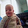 Colton joined the competition — help win amazing prizes! baby, child, smiling, indoor, pajamas, drool, hand, door, furniture, person, face, head, clothing, happy, infant, room, holding, sitting, background, casual
