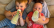 Colton joined the competition — help win amazing prizes! baby, blue_clothing, bottle, casual_clothing, child, couch, family, feeding, happy, holding, home, indoor, infant, parent, person, red_clothing, relaxing, sitting, striped_clothing, woman