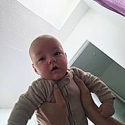 Colton joined the competition — help win amazing prizes! baby, infant, hands, person, indoor, ceiling, wall, door, clothing, onesie, curious, face, head, skin, portrait, child, room, blanket, fabric, towel