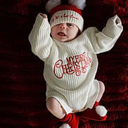 Freddie joined the competition — help win amazing prizes! baby, infant, christmas, holiday, knitwear, hat, pom_poms, red, white, blanket, cozy, cute, festive, smiling, face, person, lying_down, socks, warm, celebration