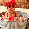 baby, child, infant, smiling, happy, outdoor, watermelon, fruit, tub, water, red_bow, headband, portrait, sitting, summer, garden, backyard, metal_container, bare_shoulders, joyful