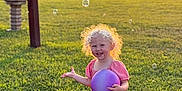 Kimber is registered to the contest to win money with this photo: child, toddler, girl, blonde, curly_hair, pink_dress, purple_ball, bubbles, grass, lawn, sunset, golden_hour, smile, happy, outdoors, play, portrait, sunlight, shoes, backyard