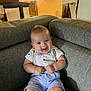 baby, child, smile, couch, suspenders, bow_tie, shirt, shorts, indoor, furniture, happy, person, infant, seated, cute, face, home, light, room, portrait