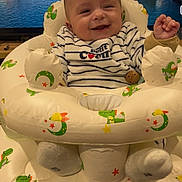 Eden participe au concours pour gagner de l'argent avec cette photo : baby, infant, smiling, inflatable_seat, baby_seat, striped_clothing, bib, socks, wooden_toy, tv_background, boats, harbor, water, indoor, happy, closeup, dinosaur_pattern, stars, moons, television