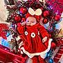 baby, infant, red_dress, headband, bow, christmas_decorations, red_baubles, pine_cones, candy_cane, wrapped_presents, fairy_lights, blanket, festive, holiday, knitted_clothing, cozy, cute, indoors, celebration, sleepy