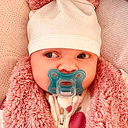 Livia a rejoint le concours — aidez-le/la à gagner de superbes lots ! baby, infant, pacifier, hat, pom_poms, pink, fluffy_jacket, cozy, cute, close_up, face, eyes, expression, warm_clothing, zipped_jacket, indoor, person, child, soft_texture, portrait