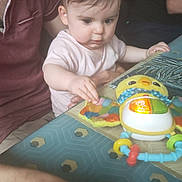 Ilyana a rejoint le concours — aidez-le/la à gagner de superbes lots ! baby, child, toy, table, adult, indoor, curious, colorful, person, hand, face, playing, clothing, pattern, furniture, light, focus, interaction, family, candid