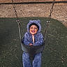 baby, child, infant, smiling, laughing, swing, playground, outdoor, park, winter_clothing, fuzzy_suit, purple_clothing, bear_hood, hat, sitting, portrait, playground_equipment, rubber_floor, wood_chips, trees