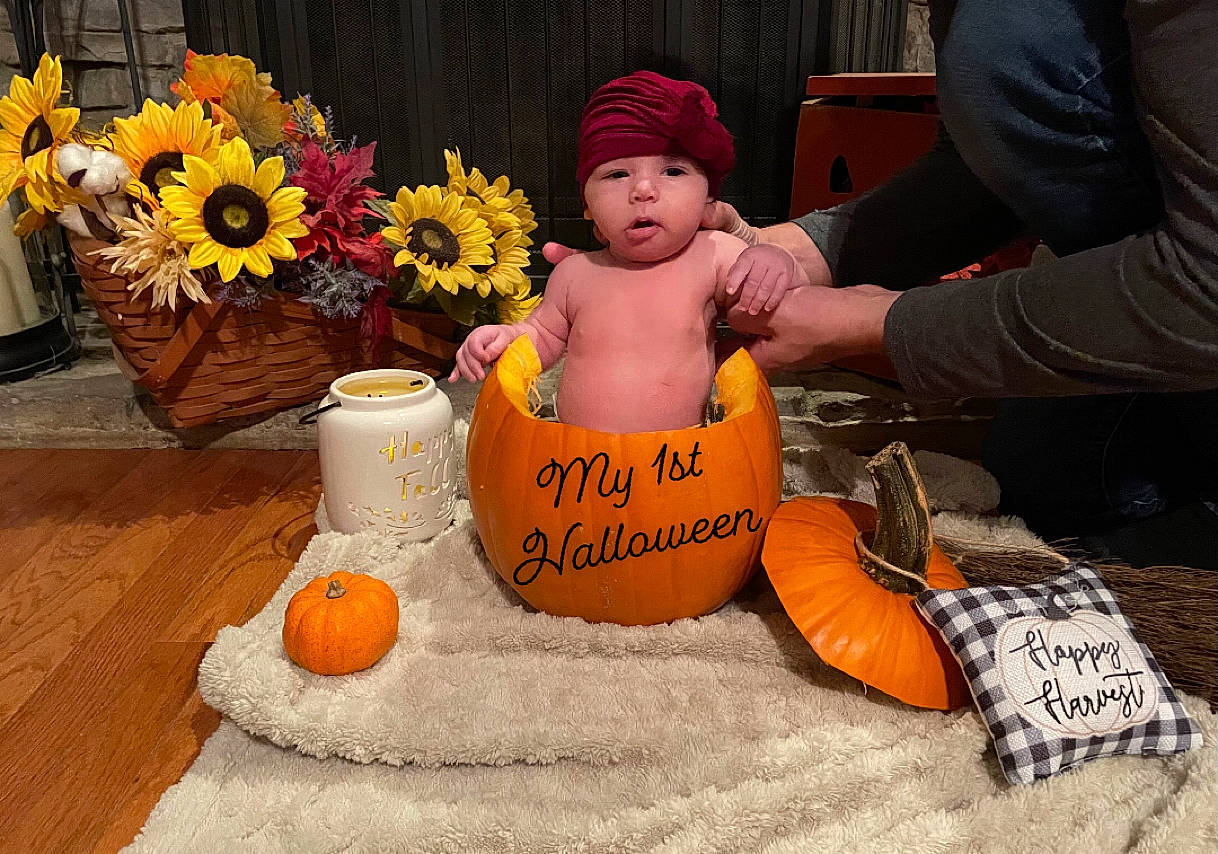 Mckenna is registered to the contest to win money with this photo: baby, calabaza, child, cucurbita, event, flooring, flower, flower_arranging, gourd, happy, headwear, natural_foods, orange, person, petal, plant, pumpkin, sitting, stuffed_toy, toddler