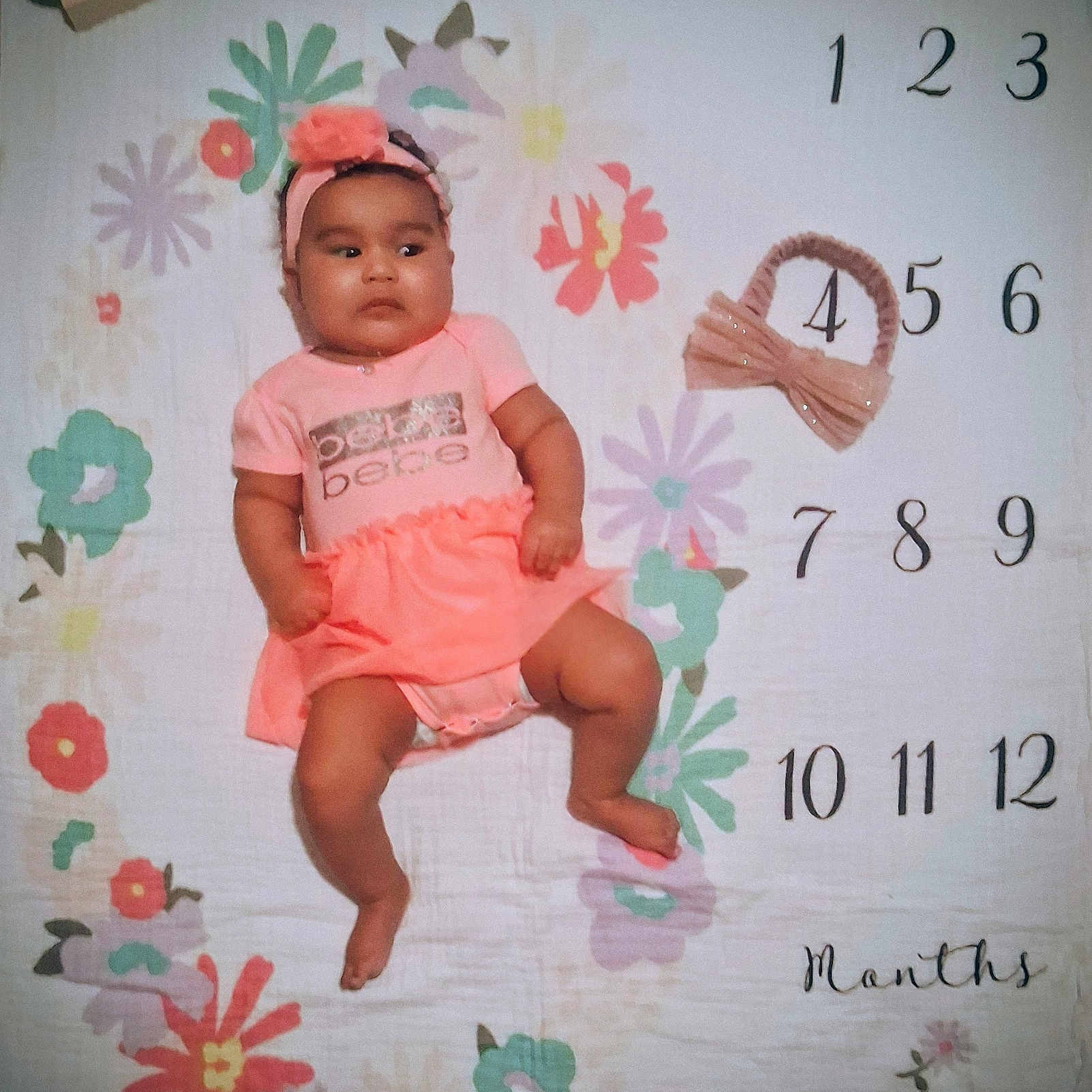 Nadaijah is registered to the contest to win money with this photo: baby, baby_girl, child, cute, floral_pattern, flower, headband, indoors, infant, lying_down, milestone_blanket, months, numbers, person, pink_clothing, portrait, skin, soft_lighting, toddler, years