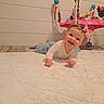 baby, child, infant, smiling, pink_bow, white_rug, floor, wooden_floor, toy, baby_toy, activity_center, indoor, person, cute, happy, crawling, headband, clothing, play, young_child