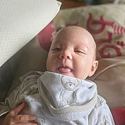 Kyra-Violet joined the competition — help win amazing prizes! baby, infant, tongue_out, teddy_bear, bib, hand, pillow, blanket, soft_fabric, cute, indoors, cozy, child, person, smiling, face, head, clothing, lying_down, nap_time