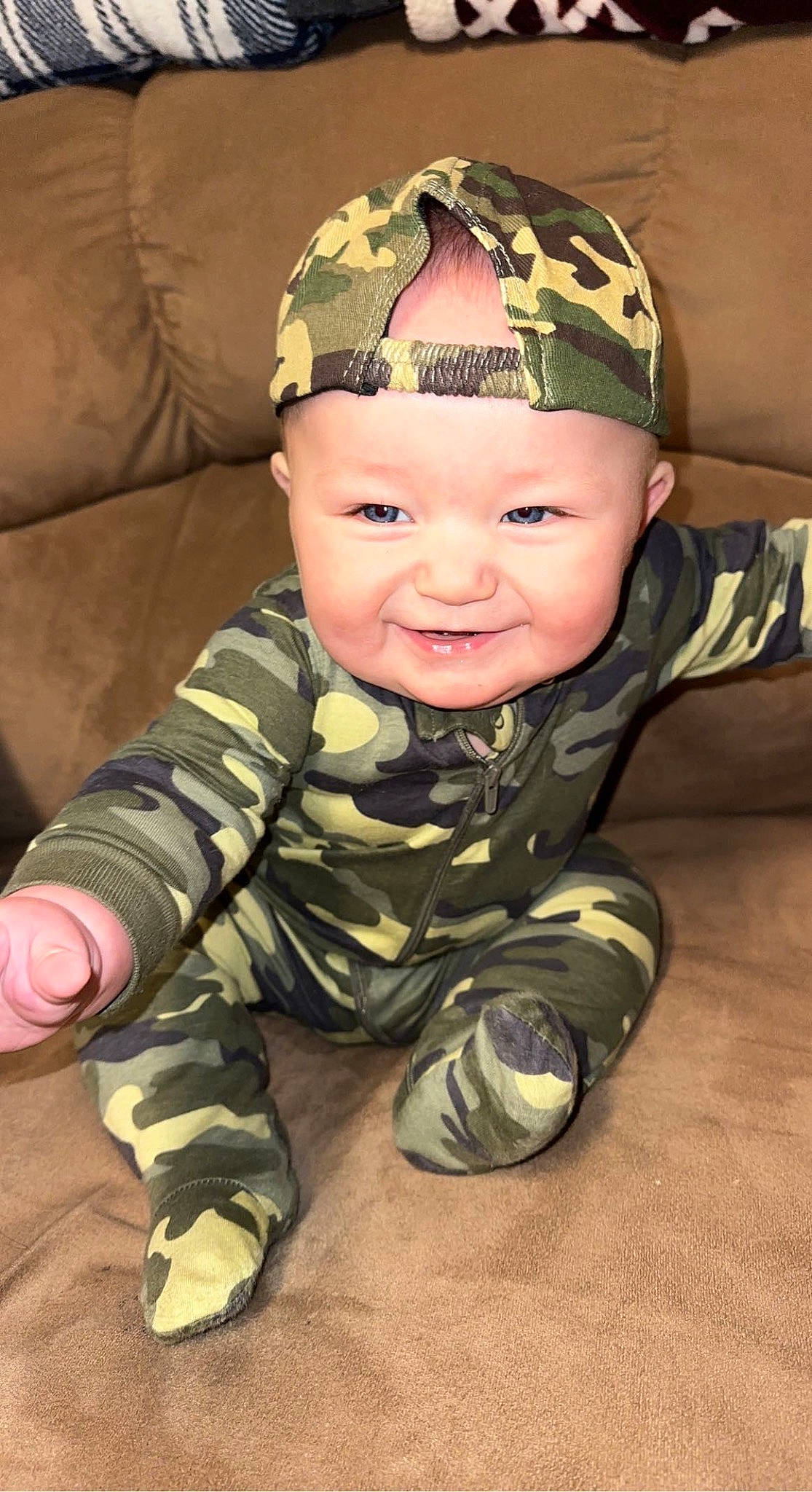 Braxton is registered to the contest to win money with this photo: baby, baby_toddler_clothing, beanie, camouflage, cap, cheek, child, comfort, crawling, eye, fashion_accessory, fun, happy, headwear, joy, military_camouflage, pattern, person, sitting, sleeve