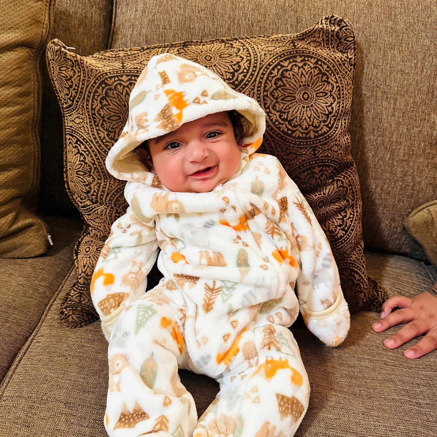 Gurarnaaz joined the competition — help win amazing prizes! baby, brown, child, couch, cozy, cute, face, furniture, hand, happy, home, hooded_onesie, indoor, infant, patterned_clothing, person, pillow, portrait, sitting, smile
