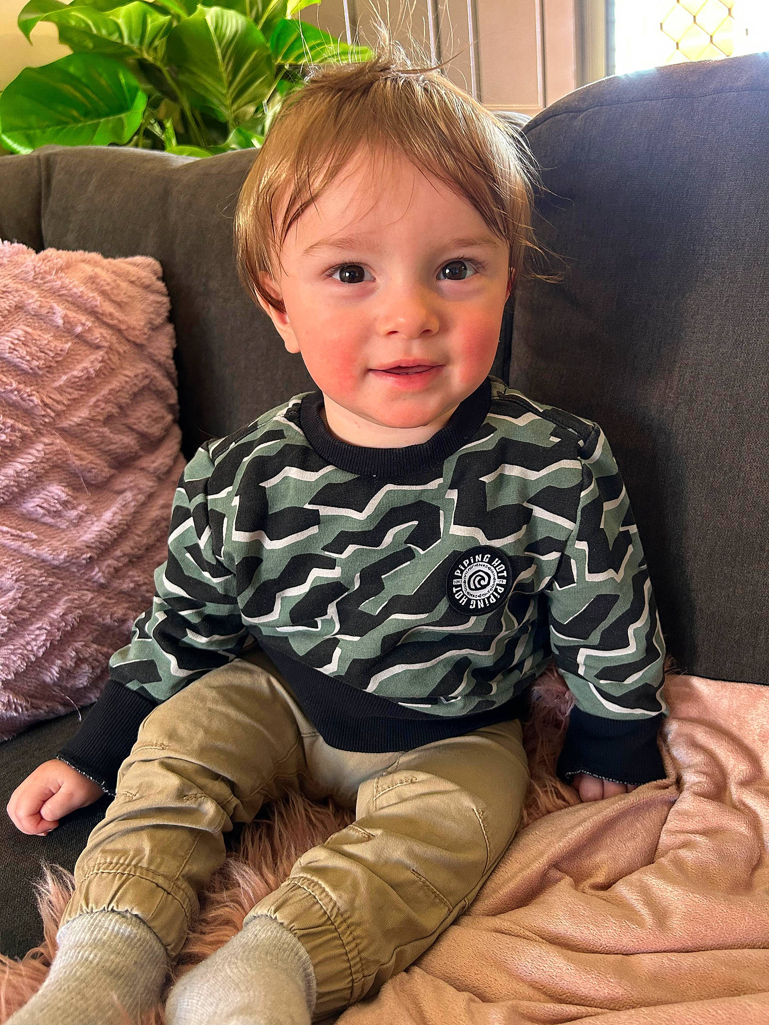 Kanan joined the competition — help win amazing prizes! baby_toddler_clothing, child, comfort, couch, face, hairstyle, head, houseplant, human_body, joy, knee, lap, living_room, person, plant, skin, sleeve, smile, sock, thigh