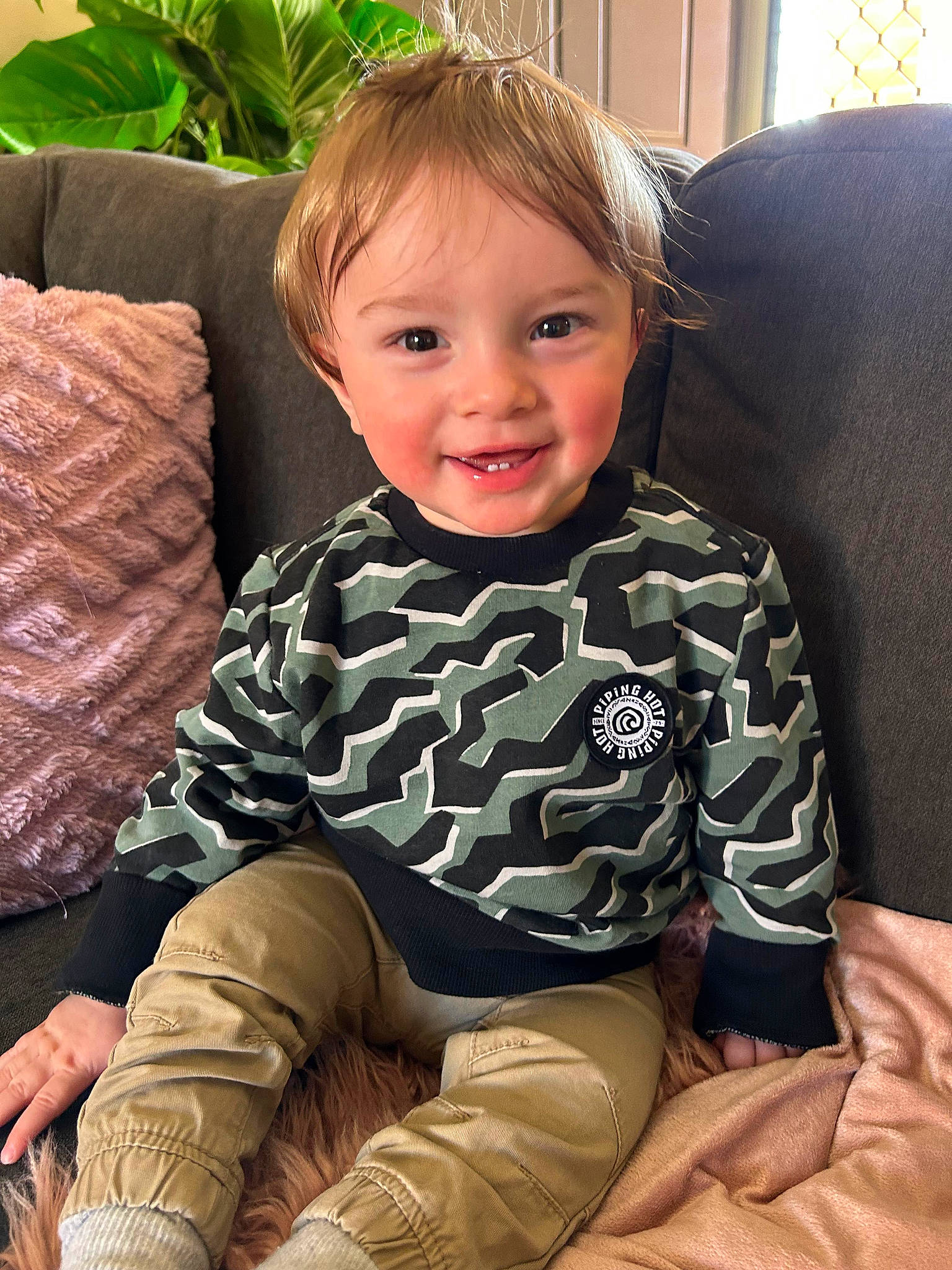 Kanan is registered to the contest to win money with this photo: baby_toddler_clothing, blond, cheek, child, comfort, couch, hairstyle, happy, head, joy, knee, lap, leg, living_room, person, plant, skin, sleeve, smile, thigh