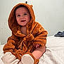 baby, child, smiling, costume, hood, brown, fuzzy, bed, blanket, feet, cute, infant, sitting, happy, indoors, person, soft, warm, clothing, portrait