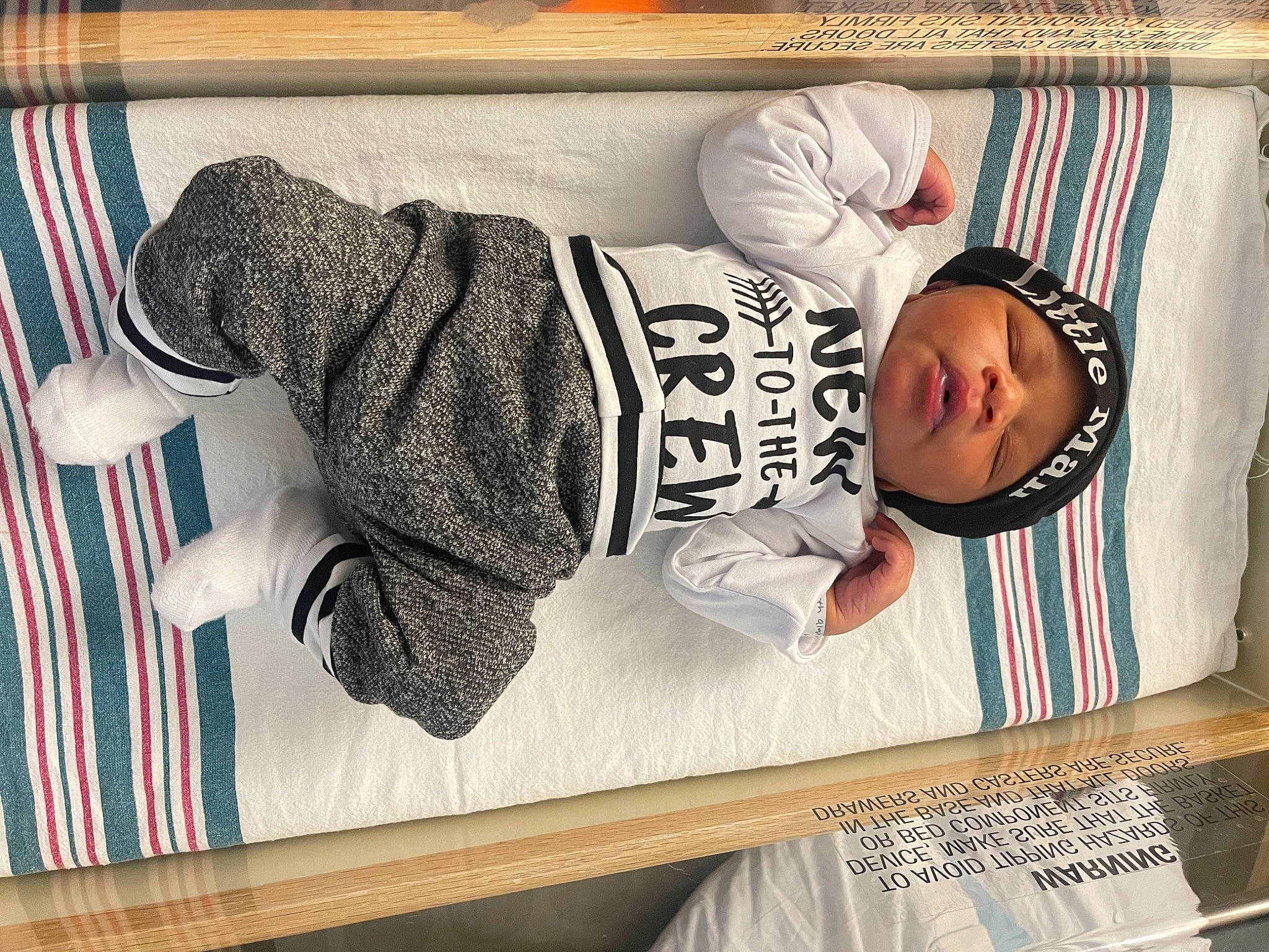 August is registered to the contest to win money with this photo: baby, baby_products, baby_safety, baby_sleeping, baby_toddler_clothing, child, comfort, headwear, infant_bed, knit_cap, linens, nap, pattern, person, room, sitting, sleeve, table, toddler, wood