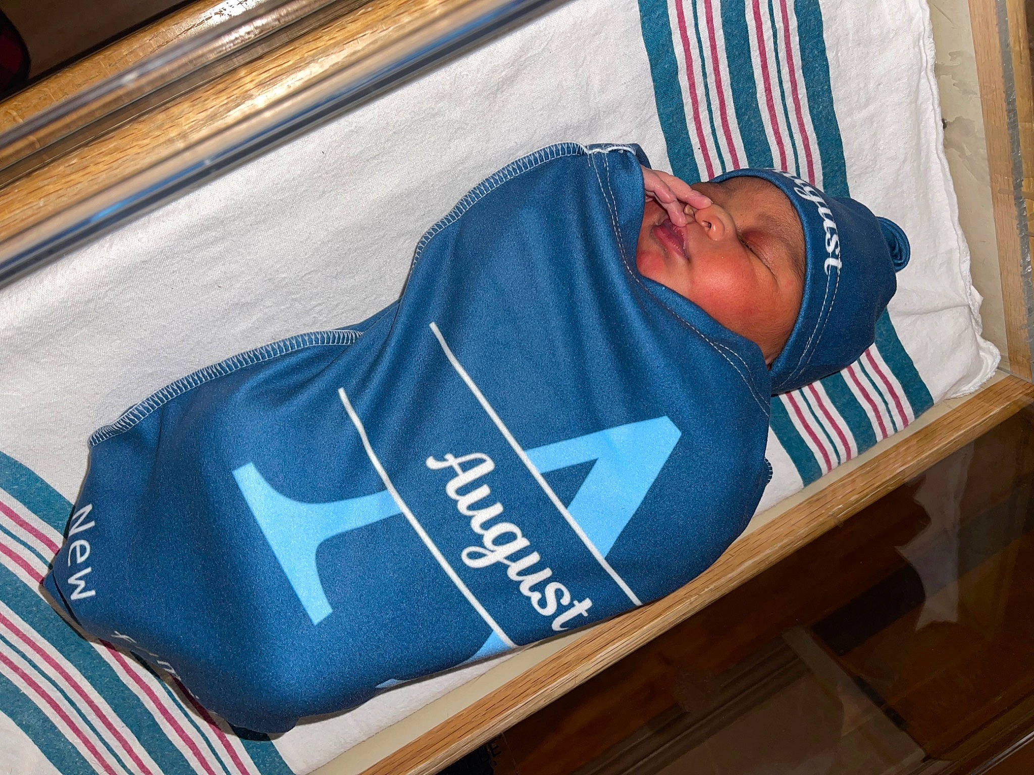 August is registered to the contest to win money with this photo: baby_safety, bag, comfort, curtain, electric_blue, font, hat, headwear, infant_bed, linens, person, personal_protective_equipment, room, sleeve, sportswear, t_shirt, transport