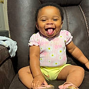 Jariyah is registered to the contest to win money with this photo: toddler, child, smile, happy, sitting, pink_clothing, yellow_clothing, sandals, leather_chair, indoor, person, cute, baby, footwear, furniture, home, tongue_out, shorts, top, joyful