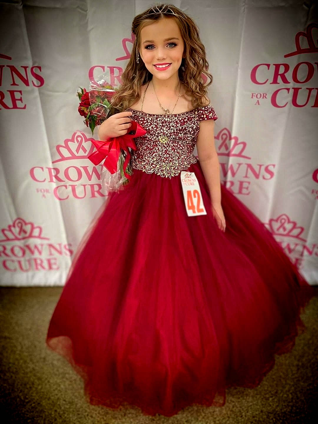 Ashlee is registered to the contest to win money with this photo: bridal_party_dress, clothing, day_dress, dress, fashion_design, flooring, gown, hairstyle, happy, head, joint, joy, magenta, neck, one_piece_garment, person, pink, shoulder, skin, sleeve