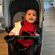 Aliana joined the competition — help win amazing prizes! baby, child, stroller, smiling, indoor, floor, red_clothing, black_clothing, happy, person, seat, baby_seat, graco, baby_toddler, head, face, hand, cushion, toy_holder, flooring