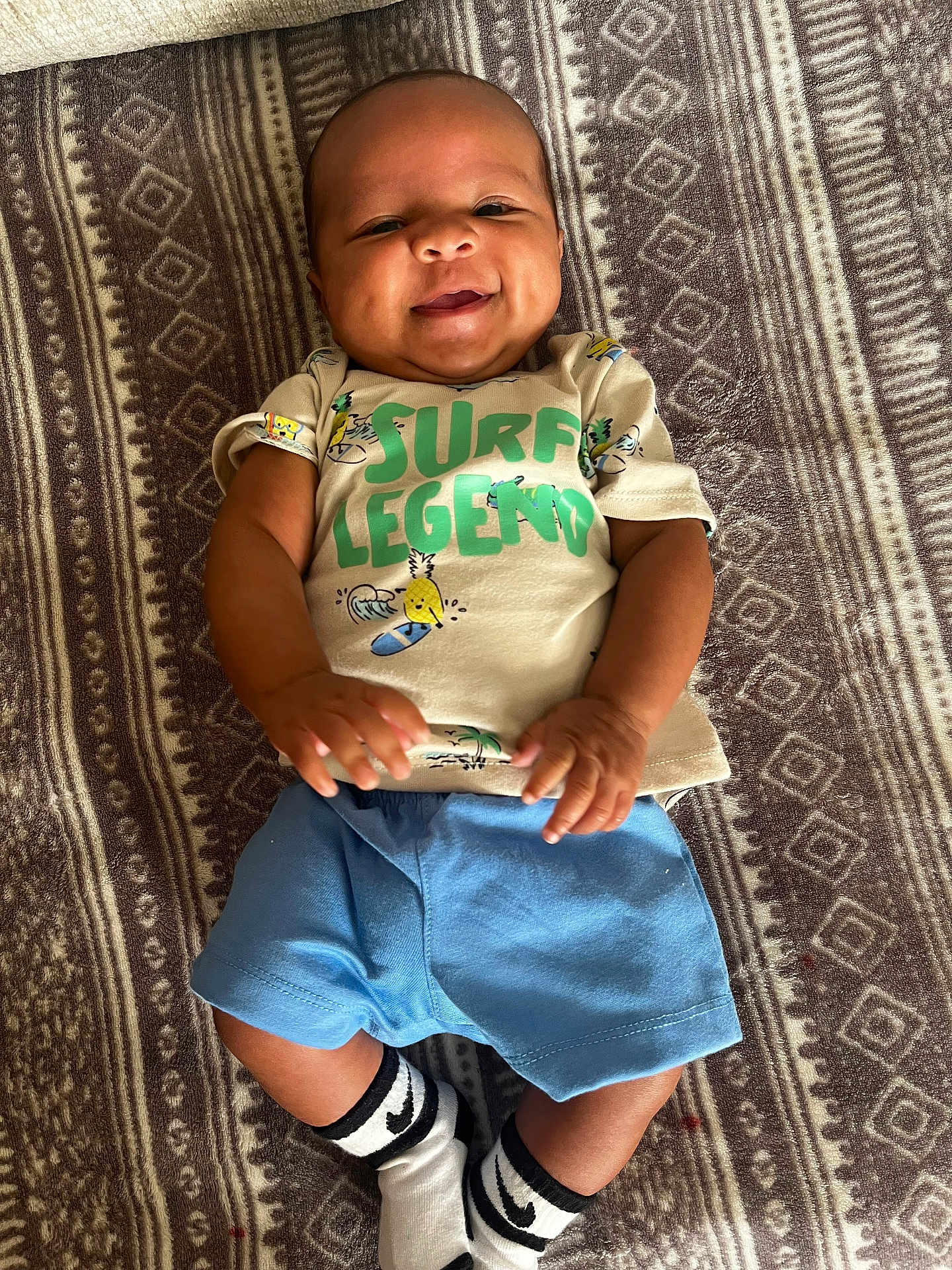 Adonis joined the competition — help win amazing prizes! baby, smiling, child, infant, tshirt, shorts, socks, lying_down, blanket, pattern, happy, cute, skin, person, indoors, portrait, young_child, clothing, casual, baby_clothes