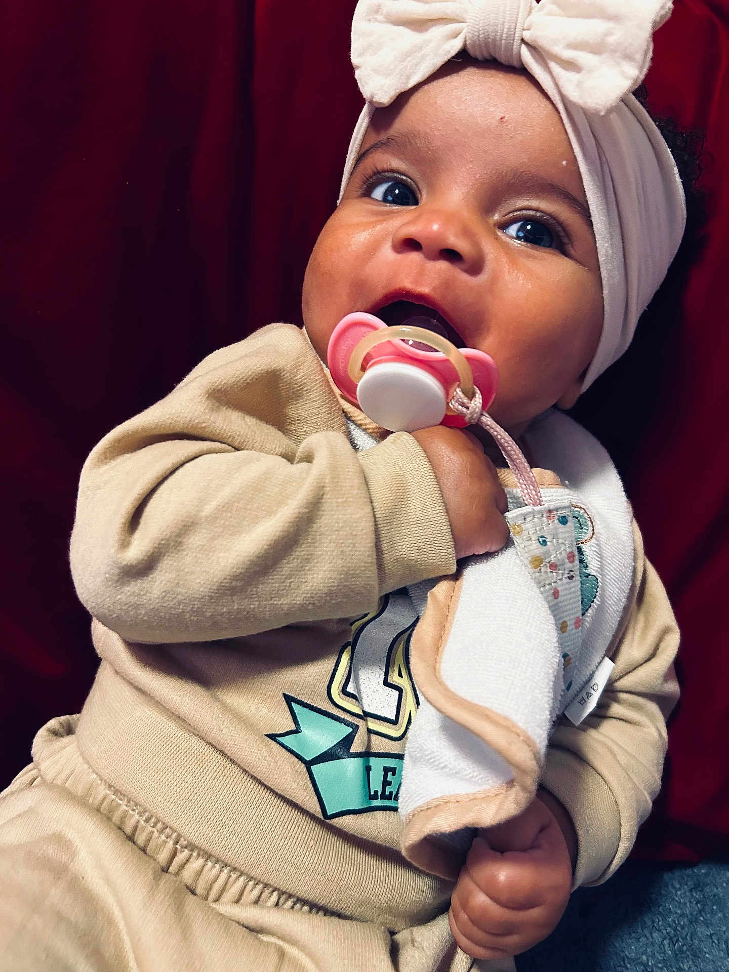 Skylah is registered to the contest to win money with this photo: baby, pacifier, headband, bow, clothing, beige, hand, face, child, cute, infant, portrait, indoors, toddler, expression, soft, fabric, warm, cozy, background