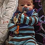 Adam is registered to the contest to win money with this photo: baby, pacifier, bib, striped_clothing, onesie, infant, face, person, indoor, cushion, blanket, bed, soft_toys, comfort, child, cute, resting, warm_lighting, patterned_fabric, calm