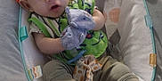 Adam is registered to the contest to win money with this photo: baby, infant, baby_seat, soft_toy, mittens, socks, cushion, pattern, colorful, green_bib, comfort, indoor, child, cute, expression, young, person, seat, cozy, playful