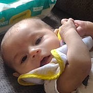 Adam joined the competition — help win amazing prizes! baby, infant, cloth, yellow_trim, face, hand, wipes, package, fabric, lying_down, soft, skin, person, closeup, blurred, indoors, baby_wipes, comfort, resting, newborn