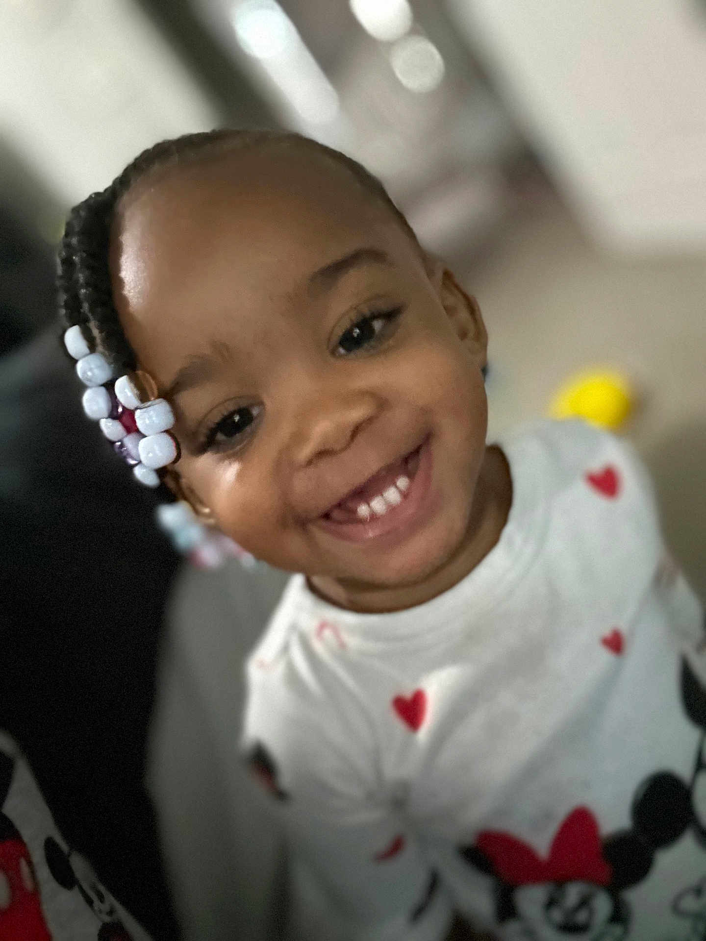 Amiyah is registered to the contest to win money with this photo: child, toddler, smiling, braided_hair, beads, white_shirt, red_hearts, minnie_mouse, indoor, portrait, happy, cute, clothing, face, person, black_hair, young_child, closeup, joyful, fashion