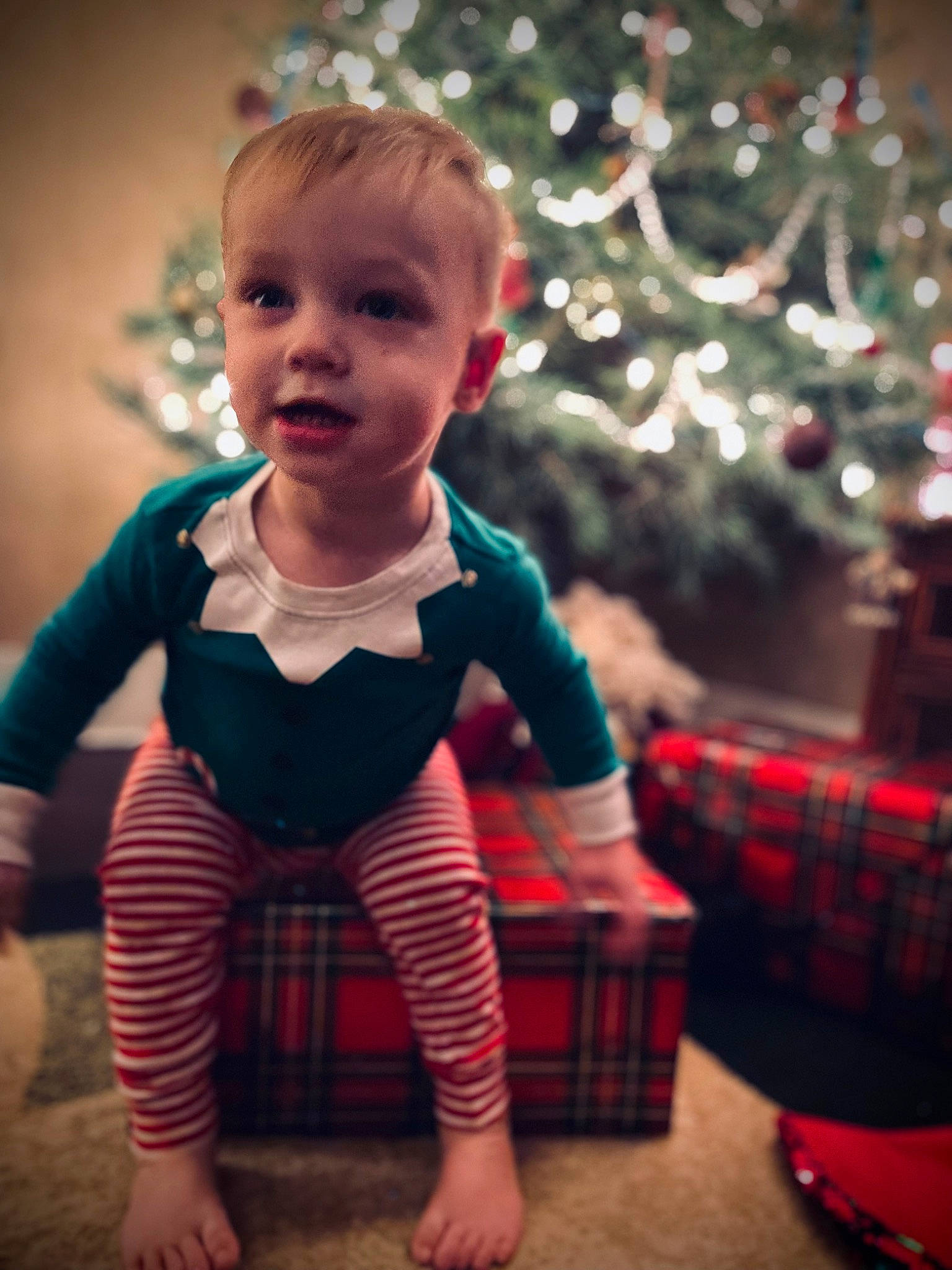 Tobias is registered to the contest to win money with this photo: baby, baby_toddler_clothing, christmas, christmas_ornament, christmas_tree, flash_photography, fun, hair, happy, head, human_body, light, pattern, person, photograph, plaid, red, sleeve, standing, tartan