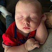Westynn is registered to the contest to win money with this photo: baby, sleeping, infant, red_clothing, closeup, peaceful, arm, hand, face, skin, newborn, portrait, indoors, soft_light, cute, resting, child, human, toddler, relaxation