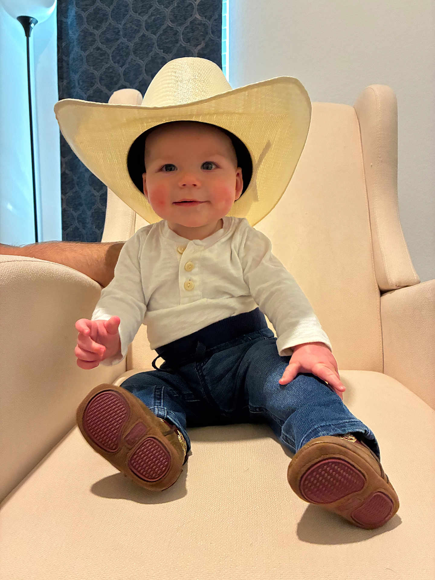Kayce joined the competition — help win amazing prizes! baby, child, cowboy_hat, hat, jeans, white_shirt, brown_shoes, armchair, furniture, indoor, smiling, face, person, cute, seated, floor_lamp, curtains, home, casual, portrait