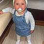 toddler, child, pacifier, headband, bow, denim, overall, dress, socks, floor, wooden_floor, couch, living_room, indoor, furniture, person, cute, baby, standing, clothing