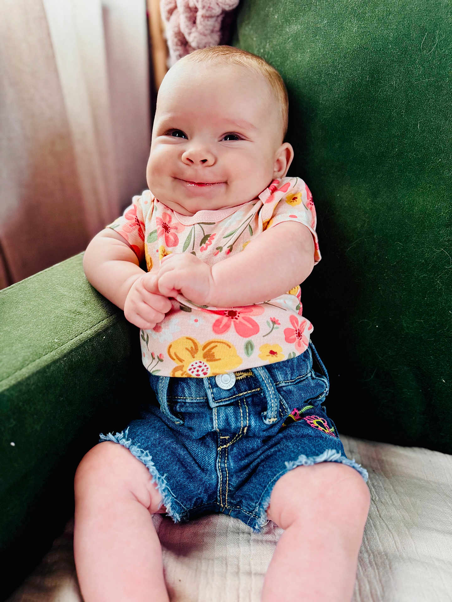 Lillie is registered to the contest to win money with this photo: baby, child, smiling, happy, denim_shorts, floral_shirt, green_chair, indoors, cute, portrait, infant, sitting, clothing, person, young_child, armchair, skin, face, expression, baby_fashion
