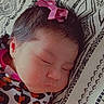 baby, sleeping, infant, portrait, face, closed_eyes, pink_bow, hair, patterned_blanket, blanket, bed, lying_down, peaceful, cute, child, newborn, clothing, patterned_clothes, indoors, close_up