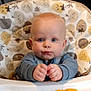 Kobi is registered to the contest to win money with this photo: baby, child, high_chair, snack, cheese_puffs, blue_eyes, face, hands, infant, indoor, table, food, expression, seat, clothing, cute, person, looking, tray, background