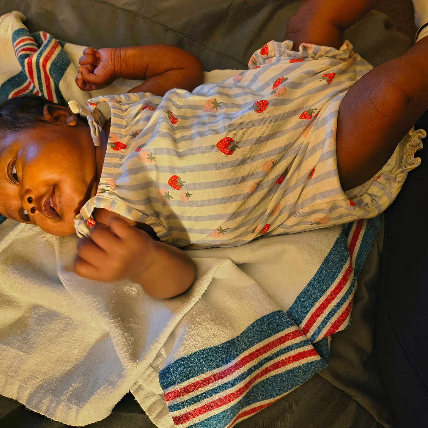 Cassidy is registered to the contest to win money with this photo: baby, infant, towel, striped_towel, strawberry_pattern, romper, clothing, lying_down, curly_hair, skin, hand, foot, socks, bed, comfortable, indoor, portrait, cute, child, person