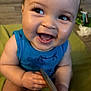 Calais is registered to the contest to win money with this photo: baby, child, smiling, laughing, blue_shirt, sitting, indoors, wooden_object, closeup, cute, happy, face, eyes, hands, skin, infant, tooth, expression, background_blur, floor